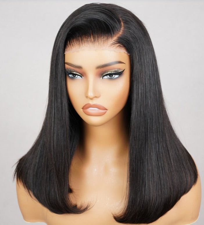Black wig on a mannequin head against a plain background